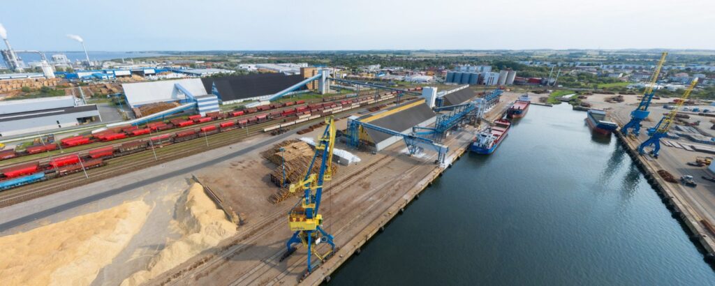 Hafen mit Zügen, Kränen und Schiffen beladen am Kai.